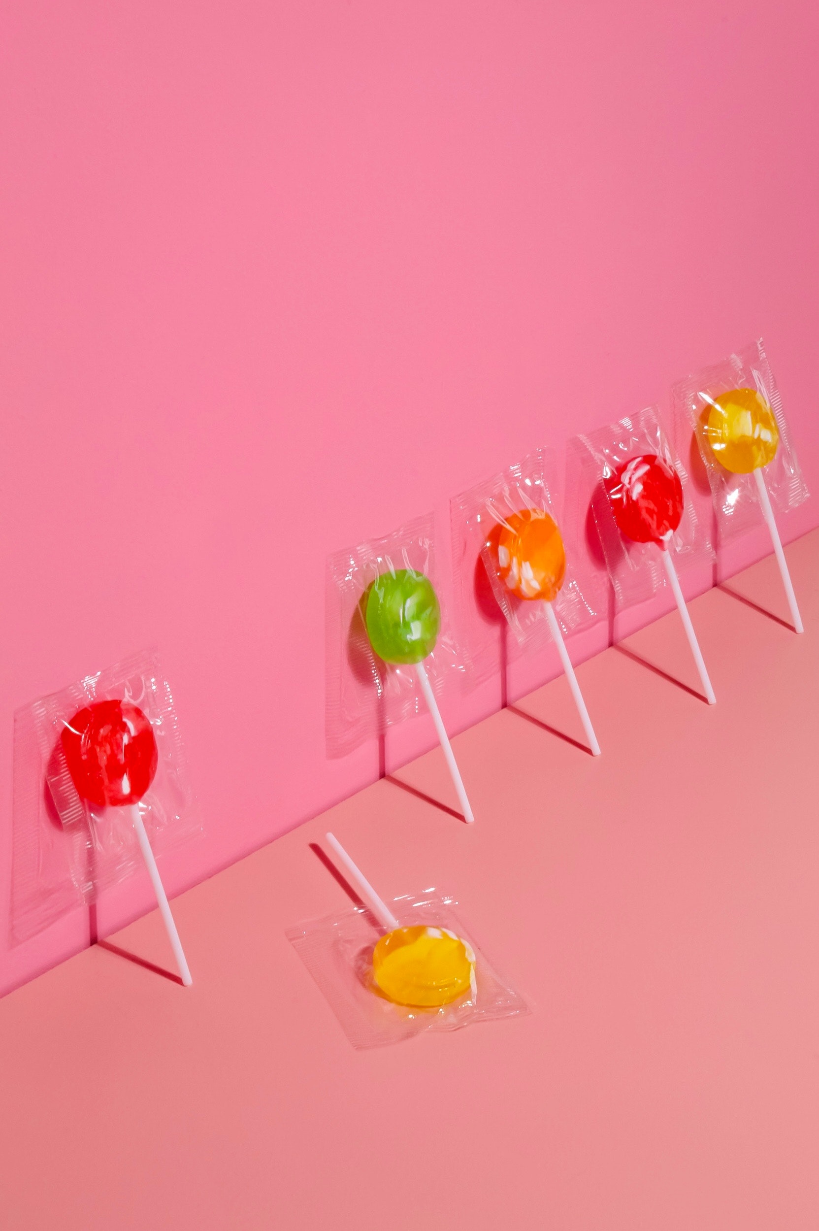 A colourful row of lollipops on a pink background — a fresh, modern take on people and organisations.